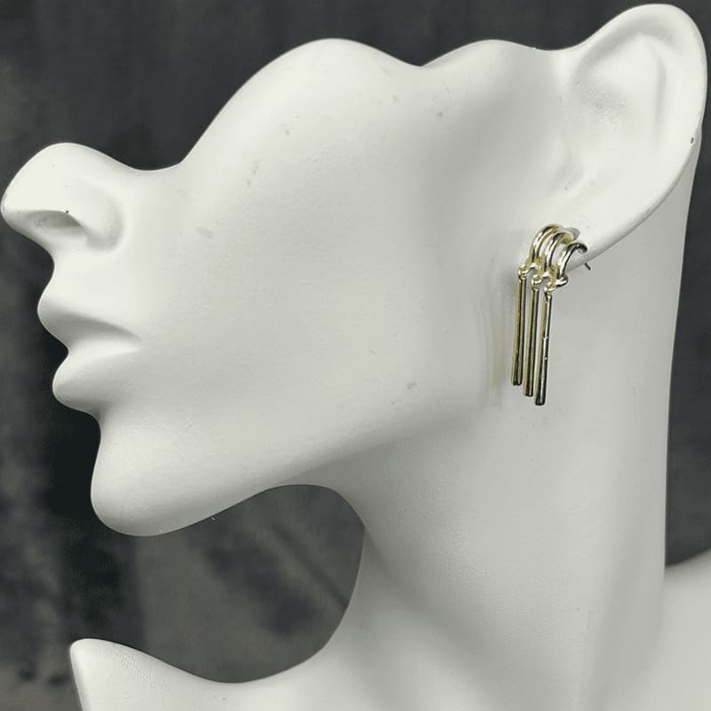 Three golden bars hang from three gold hooks that are consolidated into one post.