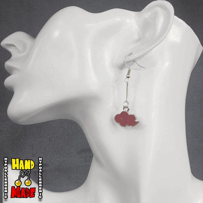 A pair of red cloud charms, dangling from a gold extender, attached to a gold French hook, displayed on a mannequin head.